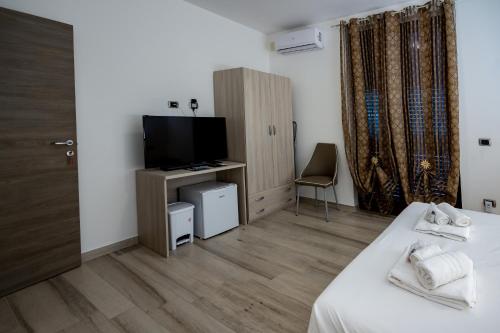 Habitación con cama, TV y silla. en ASTRA B&B, en Milazzo