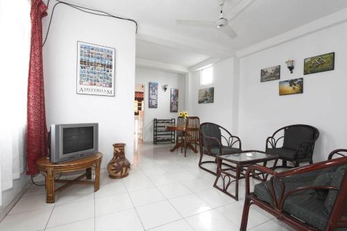 sala de estar con TV, sillas y mesa en N S Apartment, en Mount Lavinia