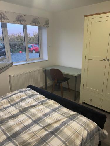 a bedroom with a bed and a desk and window at Apple Barn Guest House in Wisbech