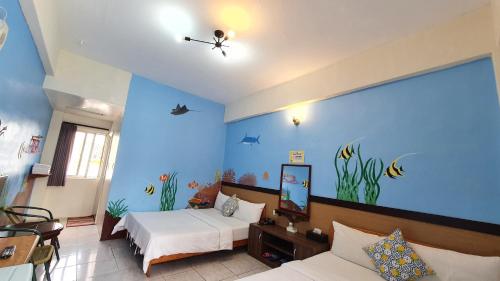 a room with two beds and an aquarium wall at Lang Jiao Ya She Homestay in Hengchun