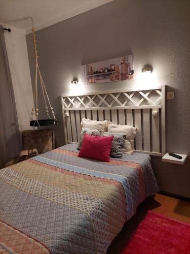 a bedroom with a large bed with a red pillow at Quartos da Vóvó in Avis