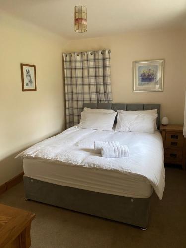 1 dormitorio con 1 cama con sábanas y almohadas blancas en Cosy Cottage in beautiful Royal Deeside, en Aboyne