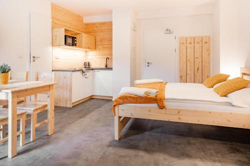 a bedroom with a bed and a table and a kitchen at Apartmány NONE in Branná