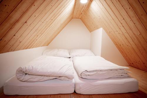 two beds in a small room with wooden ceilings at Apartmány NONE in Branná