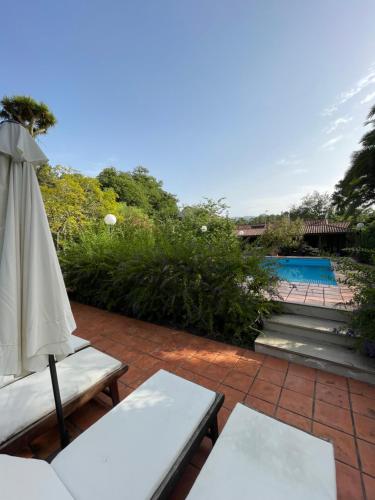 een patio met een parasol, tafels en een zwembad bij Casa Rural en medio del bosque, El Lance in Firgas