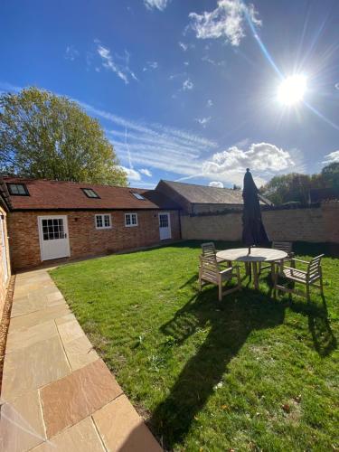 a table and two chairs and an umbrella in a yard at Old Bunsty, Milton Keynes in Milton Keynes