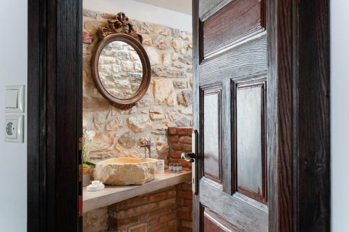 baño con espejo y pared de piedra en MAROYDA STONEHOUSE, en Panayia