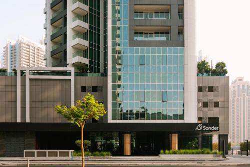 ein hohes Gebäude mit einem Baum davor in der Unterkunft Sonder Business Bay in Dubai