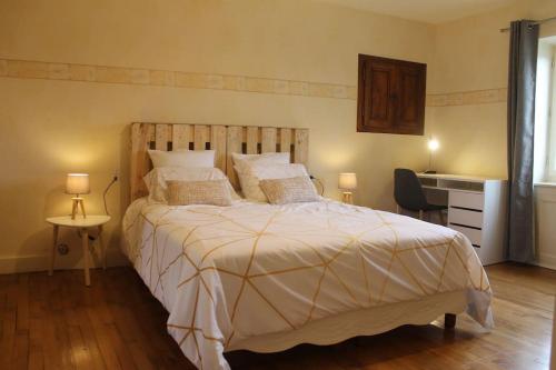 a bedroom with a large bed and a desk at Gîte Fleurs de Gamay au coeur du Beaujolais in Lancié