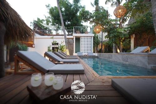 a swimming pool with chaise lounge chairs next to a house at Casa Nudista - LGBT Hotel in Zipolite