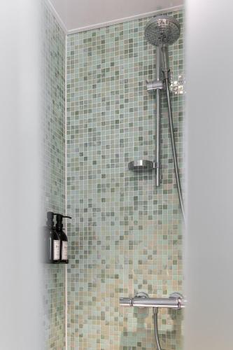 a bathroom with a shower with a tile wall at B&B Herenhuis in Izegem