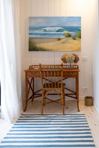 a wooden desk with a chair and a painting on the wall at Casa Flor in Punta del Este