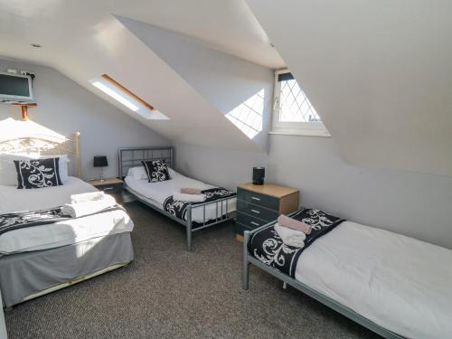 スカーバラにあるSeacrest Lodgeのベッド3台と窓が備わる屋根裏部屋