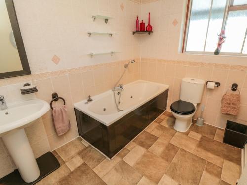 Un baño con bañera, inodoro y lavabo. en Seacrest Lodge, en Scarborough