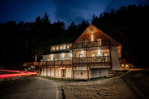 Une grande maison en bois est éclairée la nuit. dans l'établissement Apartmány NONE, à Branná