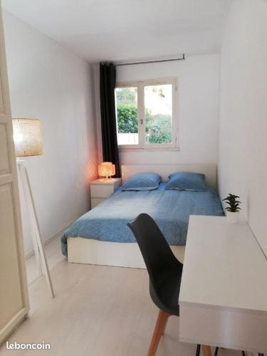une chambre avec un lit, un bureau et une fenêtre dans l'établissement Appartement de charme Saint Mandrier sur Mer, à Saint-Mandrier-sur-Mer