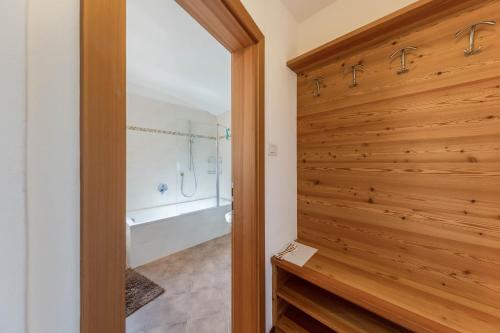a bathroom with a wooden wall and a shower stall at Florerhof Ferienwohnung Flieder in Vols am Schlern