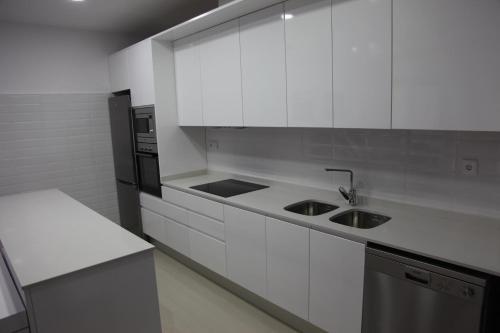 La cuisine blanche est équipée d'un évier et d'un réfrigérateur. dans l'établissement Apartamentos Alogia, Pastora, Yerbater, à Segorbe