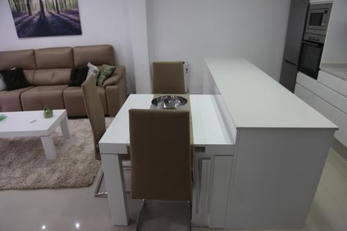 a kitchen and living room with a white table and chairs at Apartamentos Alogia, Pastora, Yerbater in Segorbe