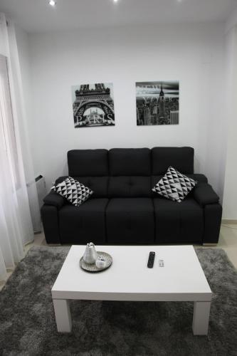 a living room with a black couch and a white coffee table at Apartamentos Alogia, Pastora, Yerbater in Segorbe
