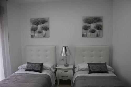 two beds in a room with two paintings on the wall at Apartamentos Alogia, Pastora, Yerbater in Segorbe