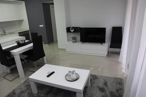 a white living room with a table and a piano at Apartamentos Alogia, Pastora, Yerbater in Segorbe
