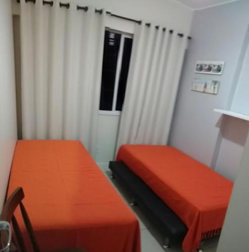 a room with two orange beds and a window at Apto em Cabo Frio com conforto e qualidade. in Cabo Frio