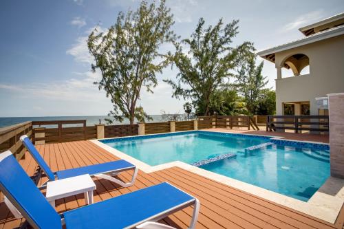 a swimming pool on a deck with chairs and the ocean at Marsh Madness in Maya Beach