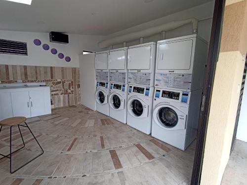 a laundry room with four washing machines and a stool at Apartamento cómodo, luz natural, zonas comunes, piscinas traer gorro, wifi, parqueadero en el Quindío in La Tebaida