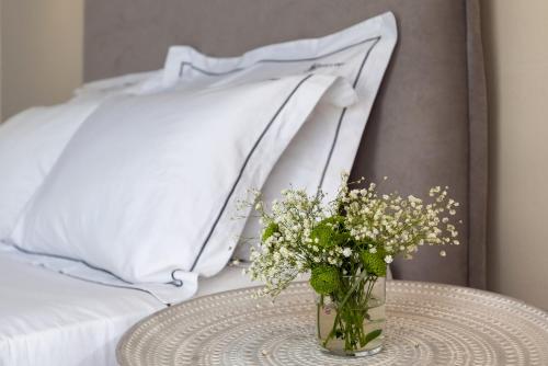 a vase of flowers on a table next to a bed at Vivianna's View in Azolimnos