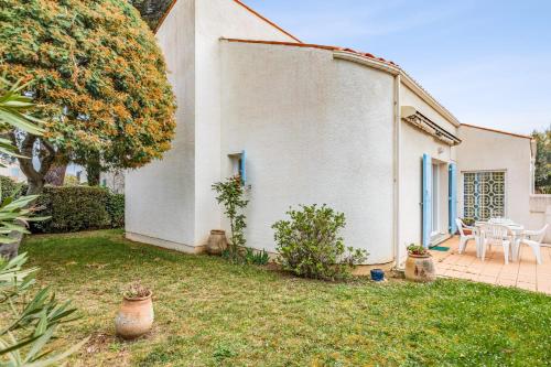 a white house with a yard with a table and chairs at Maison Avocette - Welkeys in Saint-Trojan-les-Bains