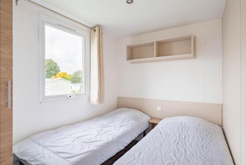 1 dormitorio con 2 camas y ventana en Mobil Home 6 pers, Normandie, Le P'tit Boujou en Litteau