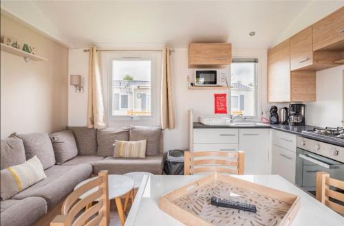 cocina y sala de estar con sofá y mesa en Mobil Home 6 pers, Normandie, Le P'tit Boujou en Litteau