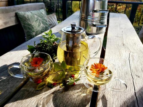 a wooden table with two glasses of tea and flowers at LOFT WAPITI in Hutisko