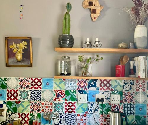 a kitchen with a colorful tile wall and a shelf at Milnerton Cottage in Cape Town