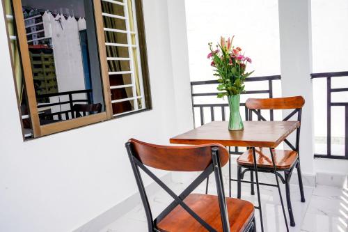 a table and chairs with a vase of flowers on it at Bliss & Beats Hostel in Phnom Penh