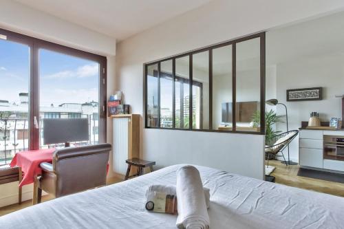 une chambre avec un lit et une grande fenêtre dans l'établissement Appartement Doumer et son balcon - Welkeys, à Paris