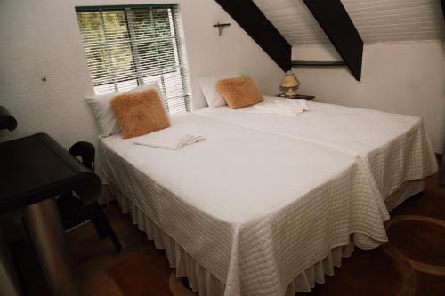 a bedroom with a large white bed with a window at The Cottage in Rustenburg
