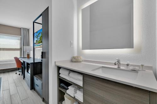 a bathroom with a sink with a mirror and a desk at Comfort Inn in South Padre Island