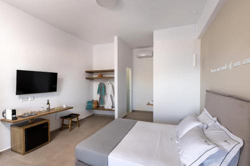 a white bedroom with a bed and a tv at Vivianna's View in Azolimnos