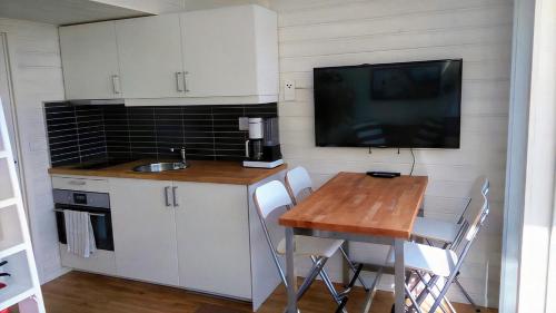 a small kitchen with a table and a tv on the wall at Strandstugan, Solviken in Rockneby