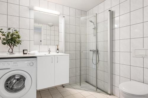 a white bathroom with a washing machine and a shower at Leilighet Beitostølen sentrum, terrasse og innendørs parkering in Beitostøl