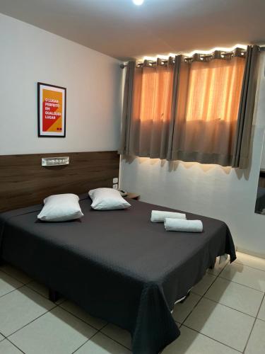 a bedroom with a large bed with two pillows at Hotel Castro in Itumbiara
