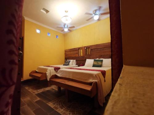 two beds in a room with yellow walls at Hotel Tihosuco Colonial in Ekpedz