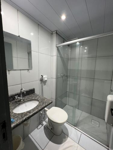 a bathroom with a shower and a toilet and a sink at Hotel Castro in Itumbiara