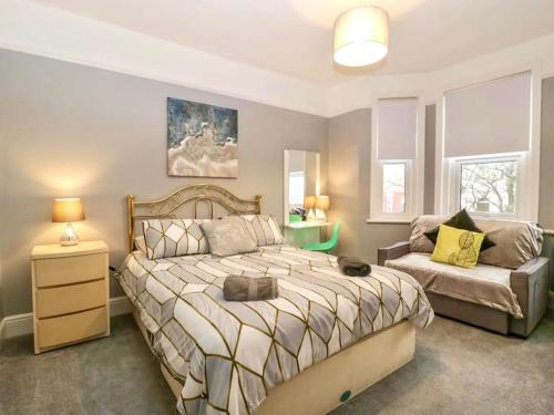 een slaapkamer met een groot bed en een bank bij Homely 4 Bedroom large house inc FREE Parking - Great Location - Fast WiFi - Smart TV - sleeps up to 7! Close to Bournemouth & Poole Town Centre & Sandbanks in Bournemouth