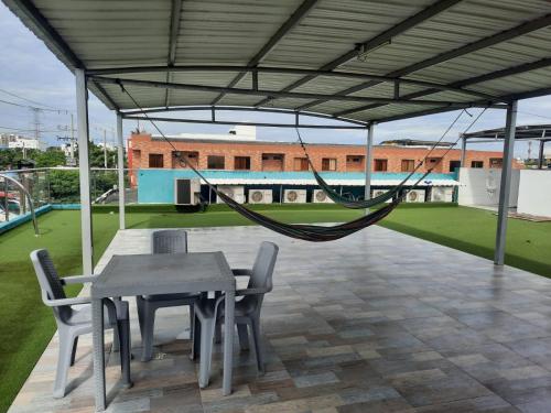 a patio with a table and chairs and a hammock at HOTEL MAR DEL CARIBE in Soledad