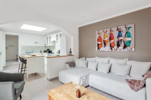 a living room with a white couch and a kitchen at Maison des Illustres - Welkeys in La Rochelle