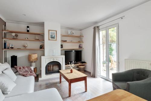 een woonkamer met een witte bank en een open haard bij Maison des Illustres - Welkeys in La Rochelle