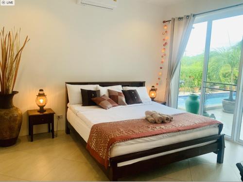 een slaapkamer met een bed en een groot raam bij House Deilert in Hua Hin